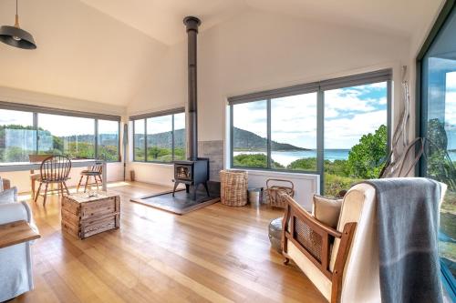 a living room with wood floors and large windows at Silver Moon at Half Moon in Bicheno