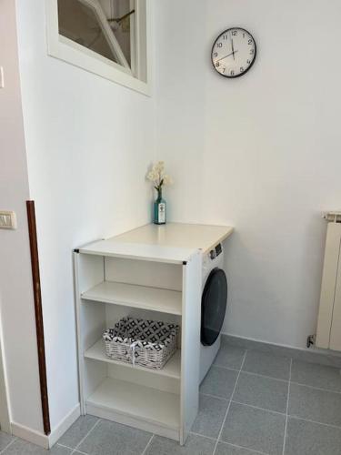 a white shelf with a clock on a wall at Il Glicine - Monolocale a due passi dal centro in Urbino
