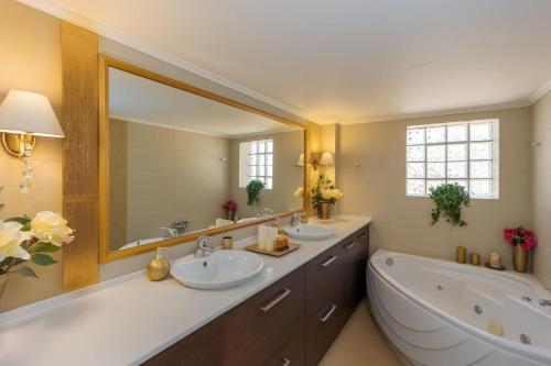 ein Badezimmer mit zwei Waschbecken, einer Badewanne und einem großen Spiegel in der Unterkunft Vista Mare Villa by Estia in Rodhiá