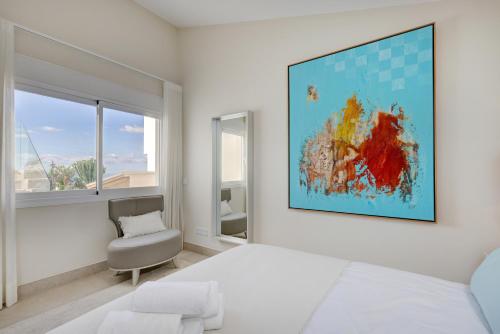 a bedroom with a bed and a chair and a painting on the wall at Villa Endless Summer in Estepona