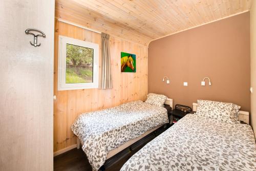 two beds in a room with wooden walls at Hakuna Matata Holidays wooden lodge with airco & pool in Greek Olive Grove in Methoni