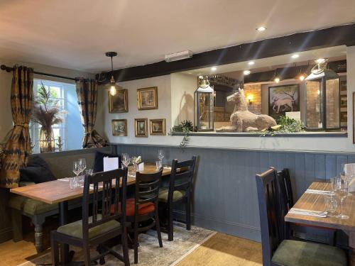 a dining room with tables and a dog on the wall at The Old Talbot Rooms Milton Keynes in Potterspury