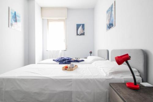 een witte slaapkamer met een groot wit bed en een rode lamp bij Raffaello House in Sestri Levante