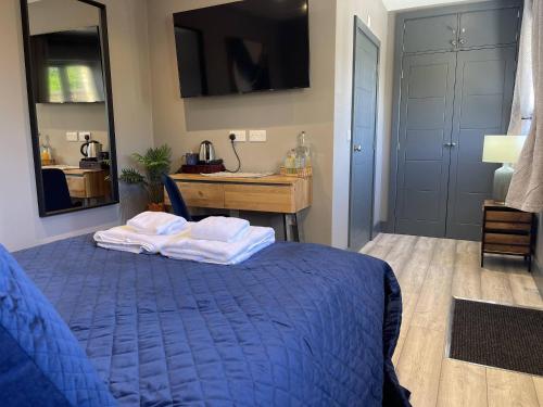 a bedroom with a blue bed and a desk at The Old Talbot Rooms Milton Keynes in Potterspury