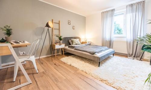 a living room with a bed and a desk and a desk at Arbio I Cozy Apartment Augsburg-Göggingen in Augsburg