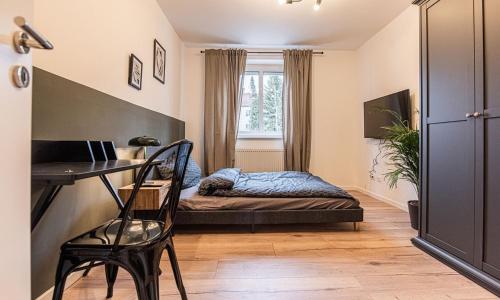 Schlafzimmer mit einem Schreibtisch und einem Bett in einem Zimmer in der Unterkunft Arbio I Cozy Apartment Augsburg-Göggingen in Augsburg