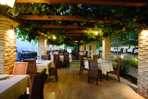 un restaurante con mesas y sillas bajo una pérgola en Villa Xanthippe, en Kalamos