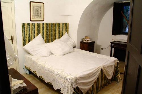 um quarto com uma cama com lençóis brancos e almofadas em Villa Tessi em Cisternino