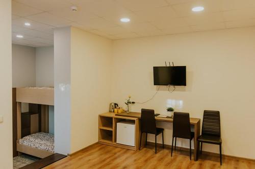Habitación con escritorio con sillas y TV en la pared. en Guest house Baltika en Ventspils