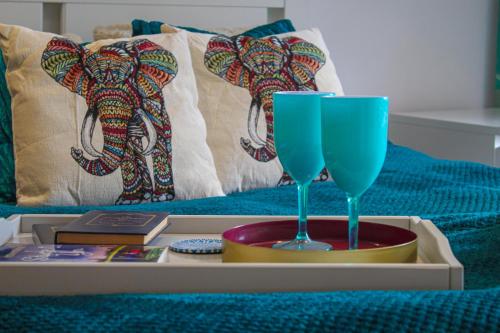 Carstairs的住宿－The Marrakech Style Loft Apartment，床上的盘子,上面有两杯蓝色的玻璃杯