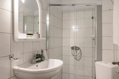 La salle de bains blanche est pourvue d'un lavabo et d'une douche. dans l'établissement Koutouki home!, à Argostóli