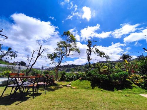 a table and chairs in a garden with a blue sky at GREENECO DA LAT HOTEL - Khách sạn Green Eco Đà Lạt in Da Lat