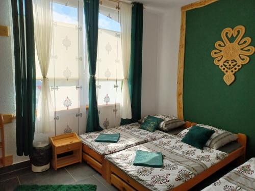 a bedroom with two beds with green walls and windows at U Siuhajów in Frydman