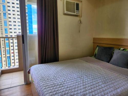 um quarto com uma cama e uma grande janela em Central Makati Condo w/ Balcony near Commercial Areas em Manila