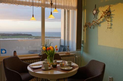 a table with a vase of flowers on it in front of a window at Appartement "Weitblick" in Heiligenhafen