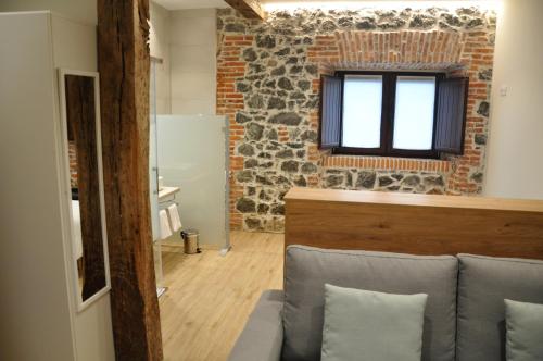 een woonkamer met een bank en een bakstenen muur bij La Lombana in Sobremazas
