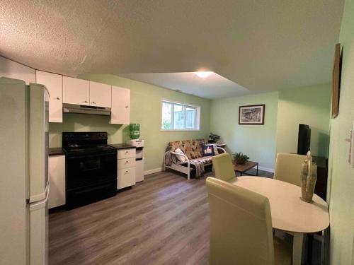 Countryroad Cozy 2 Bedrooms basement suite1 في نانايمو: مطبخ وغرفة معيشة مع طاولة وأريكة