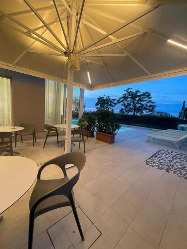 a patio with tables and chairs and an umbrella at Hotel Ascot Riccione in Riccione