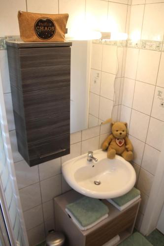 un orsacchiotto seduto su un lavandino in bagno di Ferienhaus Kärntnergmiat a Feldkirchen in Kärnten