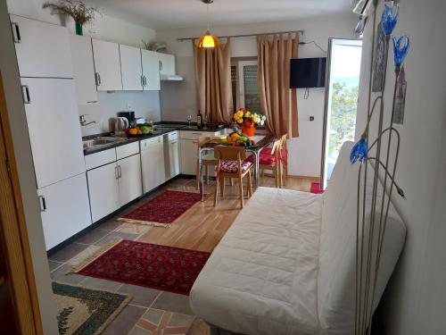una cocina con armarios blancos y una mesa con sillas. en D,apartman en Omišalj