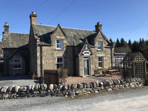 an old stone house with a stone fence in front of it at The Struan Inn Self Catering Lodge in Struan