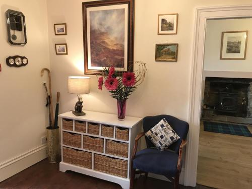 a living room with a vase of flowers on a dresser at The Struan Inn Self Catering Lodge in Struan