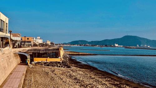 a bench on a beach next to a body of water at Family Ryokan Kawakyu with Showa Retro, private hot spring in Ibusuki