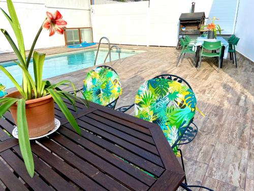 patio con mesa de madera, sillas y piscina en Casa Campoamor By Solymar Holiday en Cogollos de Guadix