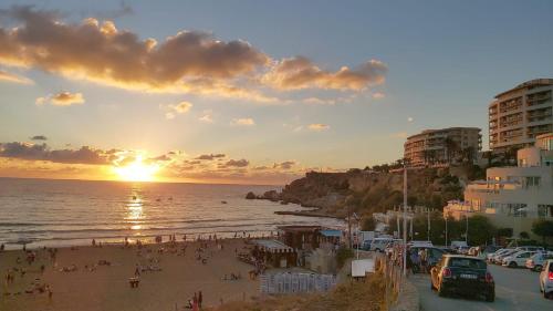 a group of people on a beach at sunset at Manor Court Luxury Apartment in St Paul's Bay