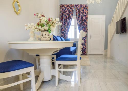 a dining room with a white table and blue chairs at Nafsika Suites in Nea Moudania
