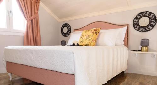 Nafsika Suites في نيا موذانيا: غرفة نوم بسرير ذو شراشف بيضاء ومخدات صفراء