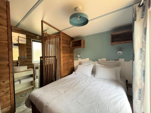 1 Schlafzimmer mit einem großen weißen Bett und einem Badezimmer in der Unterkunft Camping la Tamarissière in Agde