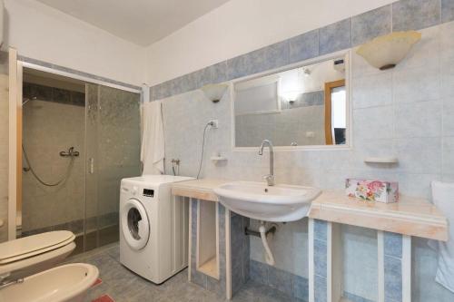 y baño con lavabo y lavadora. en Casa di Enza by BarbarHouse, en Torre San Giovanni