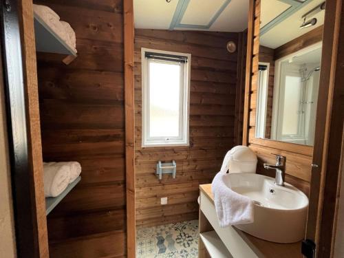 baño con paredes de madera, lavabo y ventana en Camping la Tamarissière, en Agde
