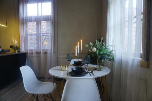 a table with two white chairs and a vase of flowers at Modiste in Kuldīga