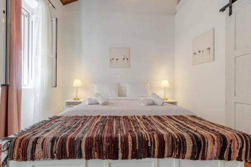 a white bedroom with a large bed with two lamps at Cozy Corfiot house in Corfu Town