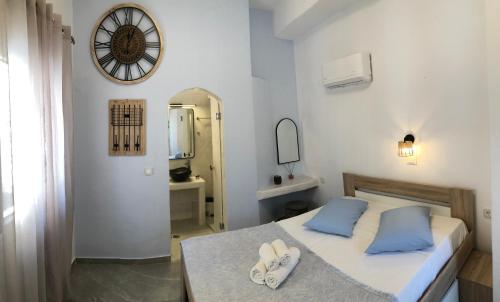 a bedroom with a bed with blue pillows and a clock at Lefteris Traditional Rooms in Fira