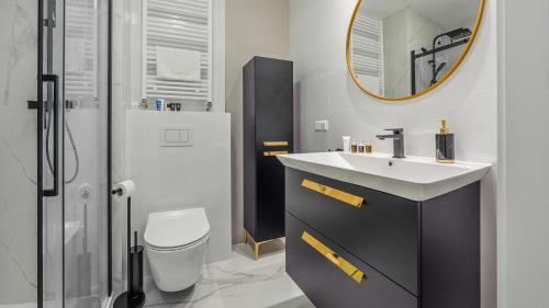 uma casa de banho com um lavatório, um WC e um espelho. em Apartament Piaskowy C 07- Posesja Kapitańska-Holiday City em Grzybowo