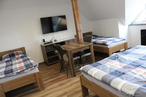 a room with two beds and a desk with a television at Penzion U Kapličky in Malá Hraštice