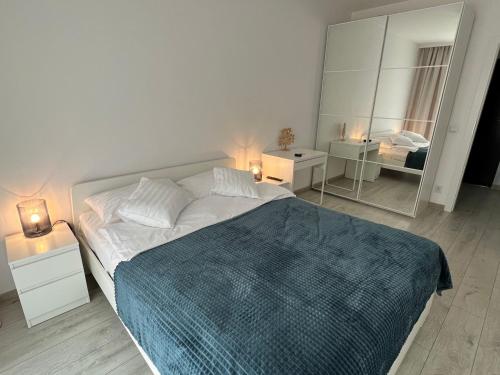 a white bedroom with a large bed and a mirror at I&M Apartments Sikorskiego Wrocław in Wrocław