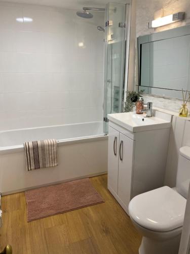 a bathroom with a toilet and a sink and a tub at The Parlour-Farm Stay-IndoorPool-Play Areas-Parkland-Woodland-Lake-Ponds-min 2 nights in Lechlade