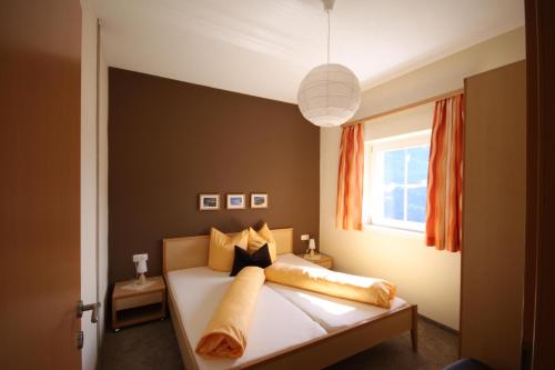 バルトロメベルクにあるPanorama Erlebnisのベッドルーム1室(オレンジ色のカーテンと窓付きのベッド1台付)