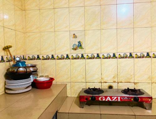 a kitchen with a stove and a wall with figurines at Mohammadia Restaurant & Guest House in Dhaka
