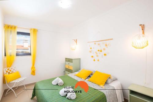 a bedroom with a bed with yellow and green sheets at #006 Foxy D by Home Holidays in Caliços
