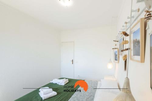 a white room with a bed with a green blanket at #006 Foxy D by Home Holidays in Caliços