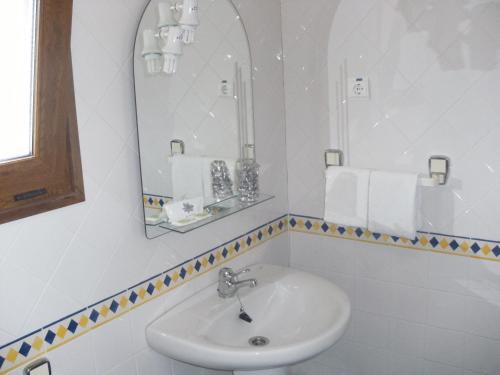 Baño blanco con lavabo y espejo en Moderna do Geres Hotel, en Gerês