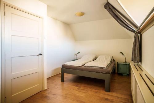 Habitación pequeña con cama y puerta en Appartement Avondzon in romantische stolpboerderij, en Warmenhuizen