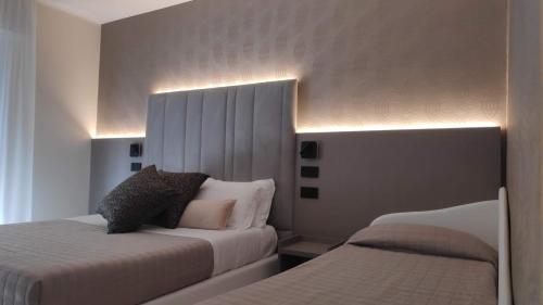 a bedroom with two beds and lights on the wall at Hotel Ascot Riccione in Riccione