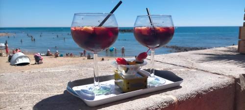 two glasses of wine sitting on a table near the beach at Studio Cap d'Agde la grande voile in Cap d'Agde
