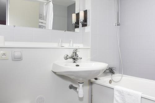 y baño blanco con lavabo y ducha. en Hôtel Inn Design Resto Novo Bourges en Bourges